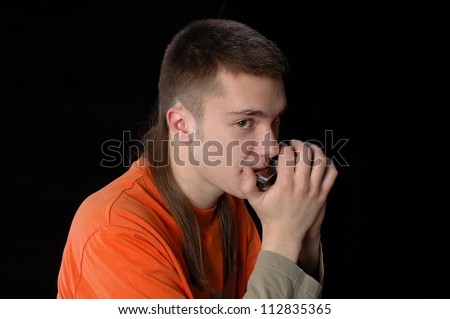 young man playing music on his harmonica on a black background ... young man playing music on his harmonica on a black background ...