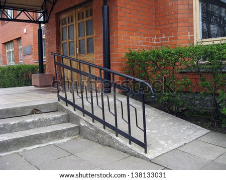 Building entrance with ramp for disabled person wheelchair - stock 