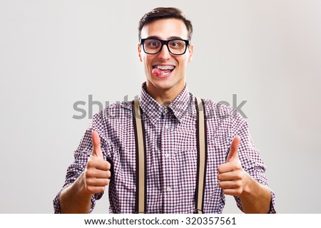  tongue and showing thumb up.Nerdy man giving thumb up - stock photo