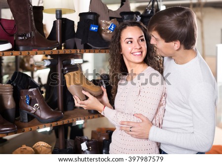 Smiling young couple buying new winter shoes in a shoe store - stock photo