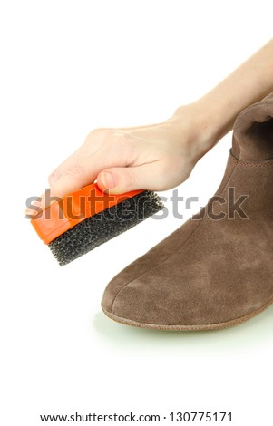Hand with brush cleaning suede shoes, isolated on white - stock photo