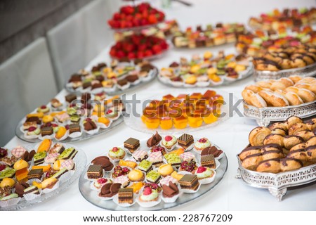 Rows of tasty looking desserts in beautiful arrangements. Mini desserts on catering buffet white tablecloth. Sweets on banquet table - picture taken during catering event - stock photo