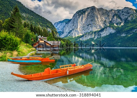 Wooden boat dock with traditional boats and high rocky mountains in 