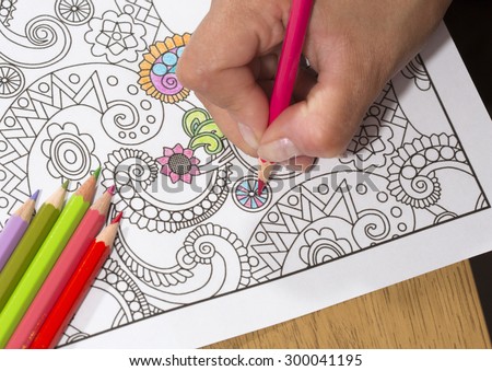 An image of a new trendy thing called adults coloring book. In this image a person is coloring an illustrative and detailed pattern for stress relieve for adults. - stock photo