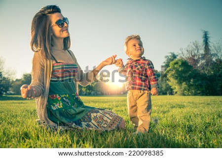 Young pretty woman with her son.Mom holding hand of a 1 year old boy - stock photo