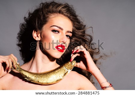 Sensual young naked girl with curly hair holding golden fish as necklace looking forward standing on - stock-photo-sensual-young-naked-girl-with-curly-hair-holding-golden-fish-as-necklace-looking-forward-standing-284881475
