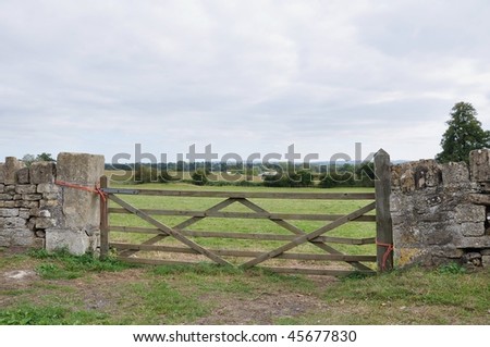 Countryside View of an Old Wooden Gate and Green Field Beyond - stock 