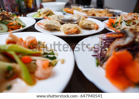 Delicious Vietnam cuisine menu in exotic food restaurant.Fried crispy shrimp rolls on white plate.Fresh colorful vegetable salads,sea food in Chinese cafe.Asian gourmet snacks.Vietnam food background