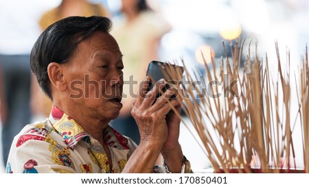 SINGAPORE - DECEMBER 21: A man holds his wallet while praying at Sri Krishnan Temple - stock-photo-singapore-december-a-man-holds-his-wallet-while-praying-at-sri-krishnan-temple-on-december-170850401
