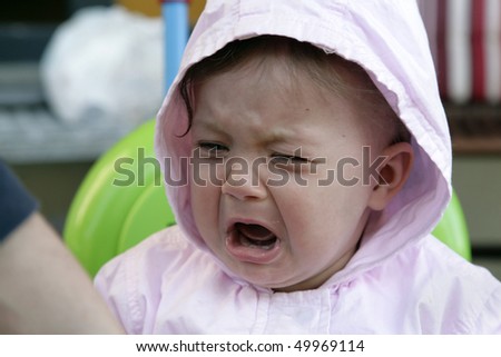 Upset Baby Girl Cries And Looks With Unsatisfied Expression Stock Photo