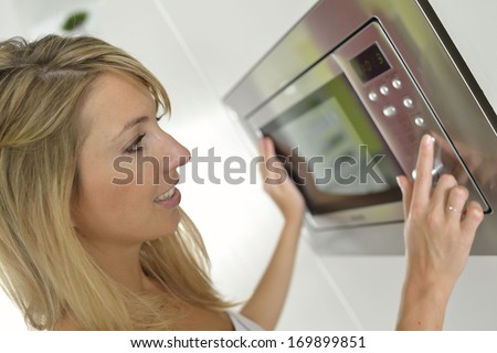 Woman at home using microwave oven - stock photo - stock-photo-woman-at-home-using-microwave-oven-169899851