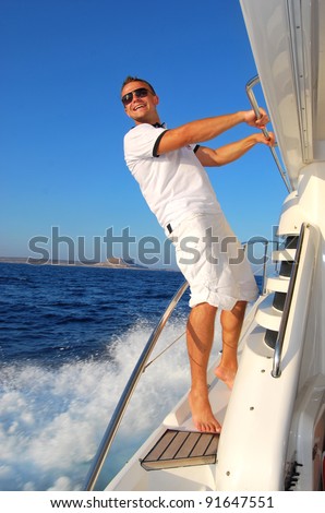 Young Sailor relaxing happily on the vacation sailboat yacht standing 