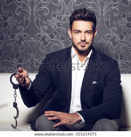 stock-photo-sexy-man-holding-handcuffs-sit-on-sofa-bdsm-355214375.jpg