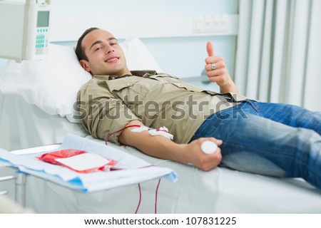 Smiling transfused patient lying on a bed in hospital ward - stock photo