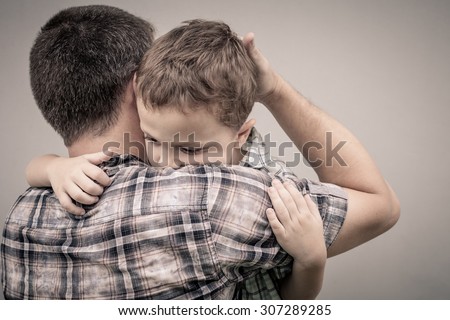 Sad Son Hugging His Dad Near Wall At The Day Time - Stock Photo