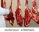 Small photo of Butcher chooses sliced fresh beef pieces for the buyer in the rural market