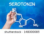 Small photo of hand with pen drawing the chemical formula of serotonin