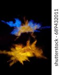 Small photo of Multi cloud blasting powder paint and flour combined, explode in front of a black background to give off fantastic golden multi color forms