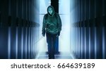 Small photo of Masked Hacker Wearing Hoodies Walks in Through Data Center Corridor.