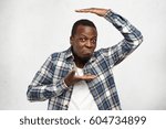Small photo of Stylish young dark-skinned man making wry mouth having disappointed expression, gesturing with both hands, holding palms in front of him as if showing size of something. Body language concept