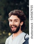 Small photo of Widely smiling man close-up. Portrait of young bearded guy looking at camera with sly look. Joy, joke, fun, leg-pull, stand-up concept