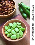 Small photo of Raw broad beans (lat. Vicia faba) in bowl with pods and roasted broad beans in the back, photographed with natural light (Selective Focus, Focus on the top of the beans)