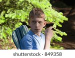 Small photo of teenager in rapt attention - holding his camera and sitting in front of a fir tree - adobe RGB