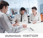 Small photo of signing contract on partners back, young couple on business meeting with life insurance and bank loan agent at modern office interior