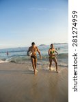 Small photo of RIO DE JANEIRO, BRAZIL - APRIL 1, 2014: Young Brazilian man and woman walk with football on the shore of Ipanema Beach at Posto 9, a famous gathering place for sport and recreation.
