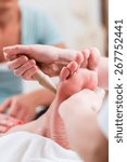 Small photo of Women at reflexology having foot massaged or pressed with wooden stick