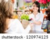 Shopping woman at the checkout paying by card - stock photo