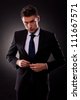 businessman buttoning jacket, getting dressed, on dark background - stock photo
