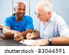 Young college student tutoring an older classmate. - stock photo