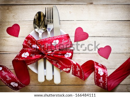Valentines day table setting with plate, knife, fork, red ribbon and hearts/ Holidays background/ Valentines day background