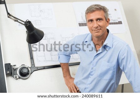 Portrait Of Male Architect With Blueprint At Office