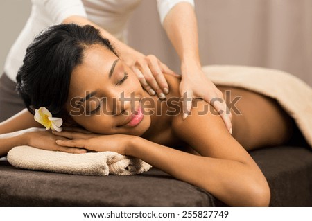 Closeup of happy african woman receiving back massage at salon spa