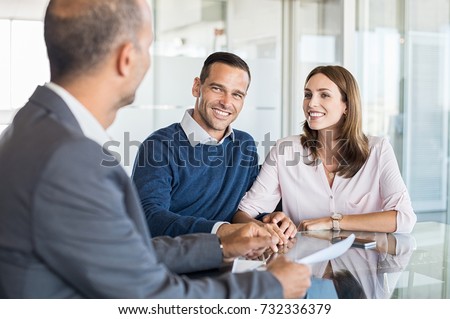 Mature financial advisor showing report to young couple for their investment. Salesman and positive couple talking about purchase. Happy couple consulting financial agent for loan.