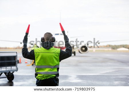 Ground Crew Signaling To Airplane