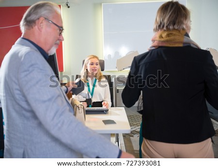 Staff With Senior Passengers At Airport Check-in Desk