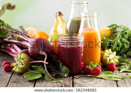 Variety of fresh vegetable and fruit juices in bottles and mason jar.