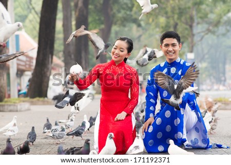 Happy Vietnamese couple among pigeons on the street