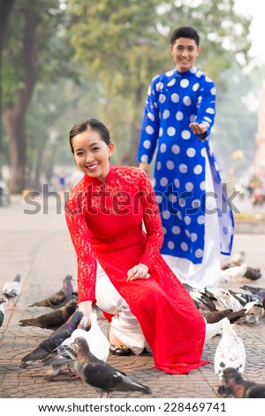 Lovely Vietnamese couple in traditional clothes feeding pigeons