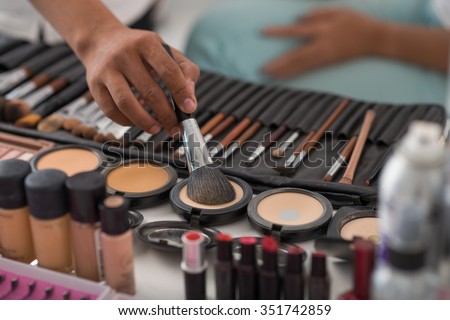 Make-up artist using natural animal hair brush to apply pressed powder