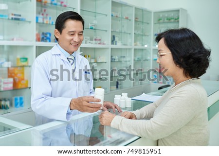 Pharmacist giving tablets to senior female customer