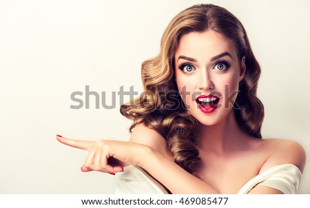 https://thumb7.shutterstock.com/display_pic_with_logo/1054231/469085477/stock-photo-woman-surprise-showing-product-beautiful-girl-with-curly-hair-pointing-to-the-side-presenting-469085477.jpg