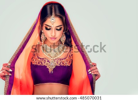 Portrait of beautiful indian girl . Young hindu woman model with tatoo mehndi and kundan jewelry . Traditional Indian costume lehenga choli .