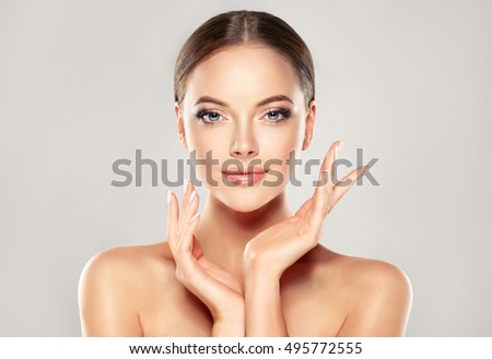 Beautiful Young Woman with Clean Fresh Skin touch own face . Facial treatment . Cosmetology , beauty and spa .