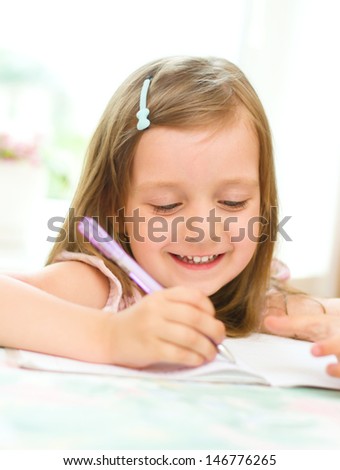 cute happy little girl writing something in her notebook