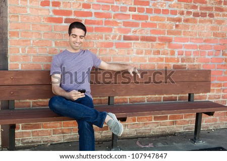 stock-photo-an-attractive-young-man-sitting-on-a-bench-outside-using-his-cell-phone-wearing-a-purple-shirt-and-107947847.jpg