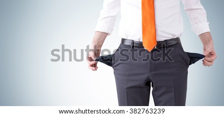 businessman with an orange tie turning his empty pockets inside out. Front view, no head. Grey background. Concept of bankruptcy.